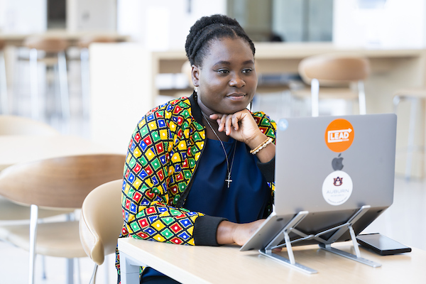 student at a table in a common area working on her laptop