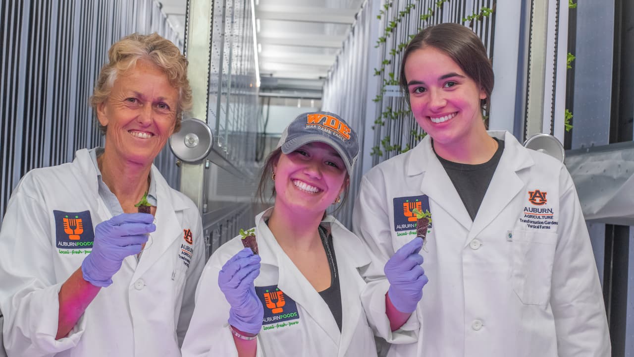 three people posing with seedlings