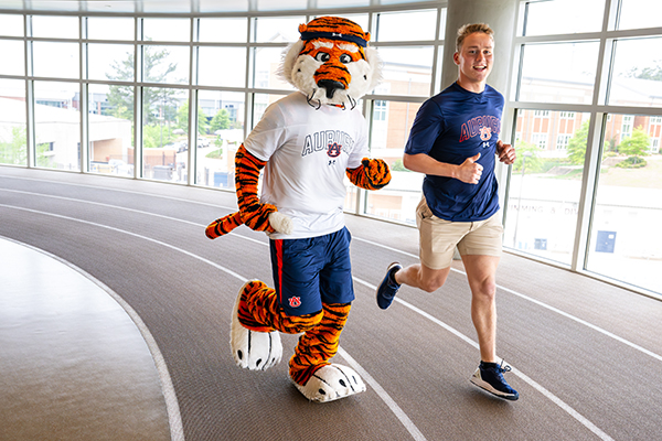 Aubie and student running the indoor track