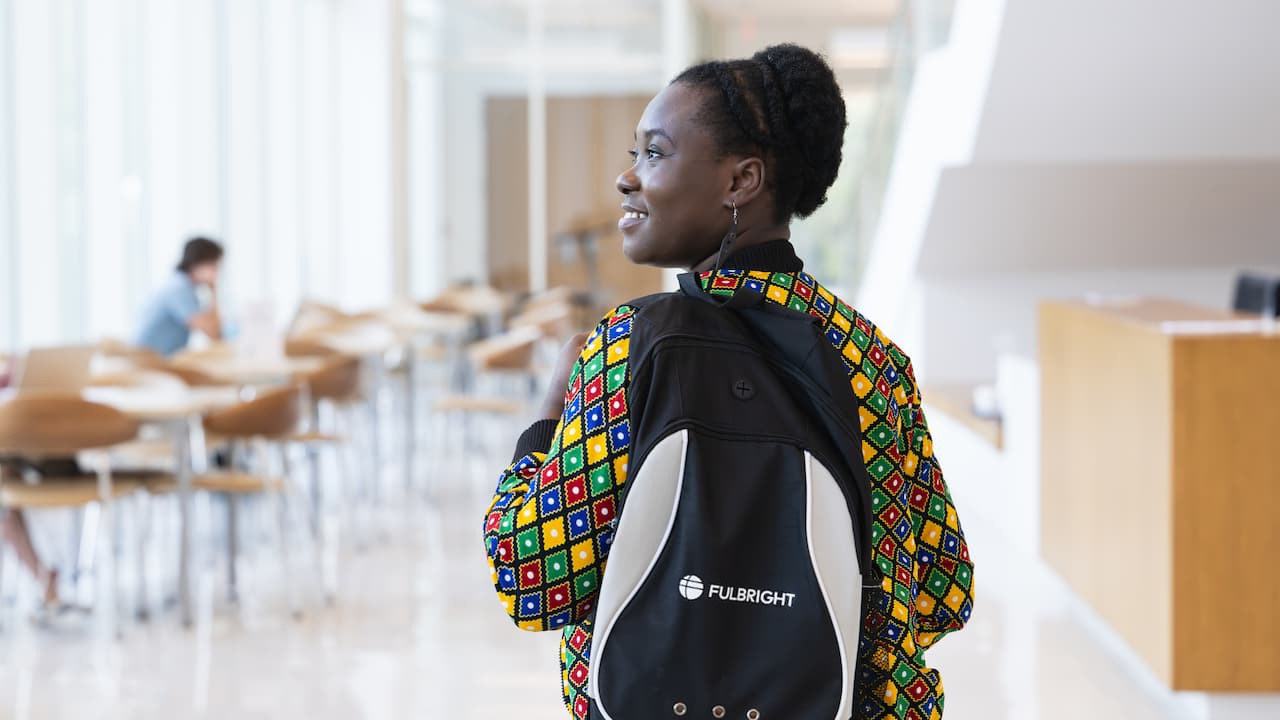 graduate student with a backpack standing in an academic building 