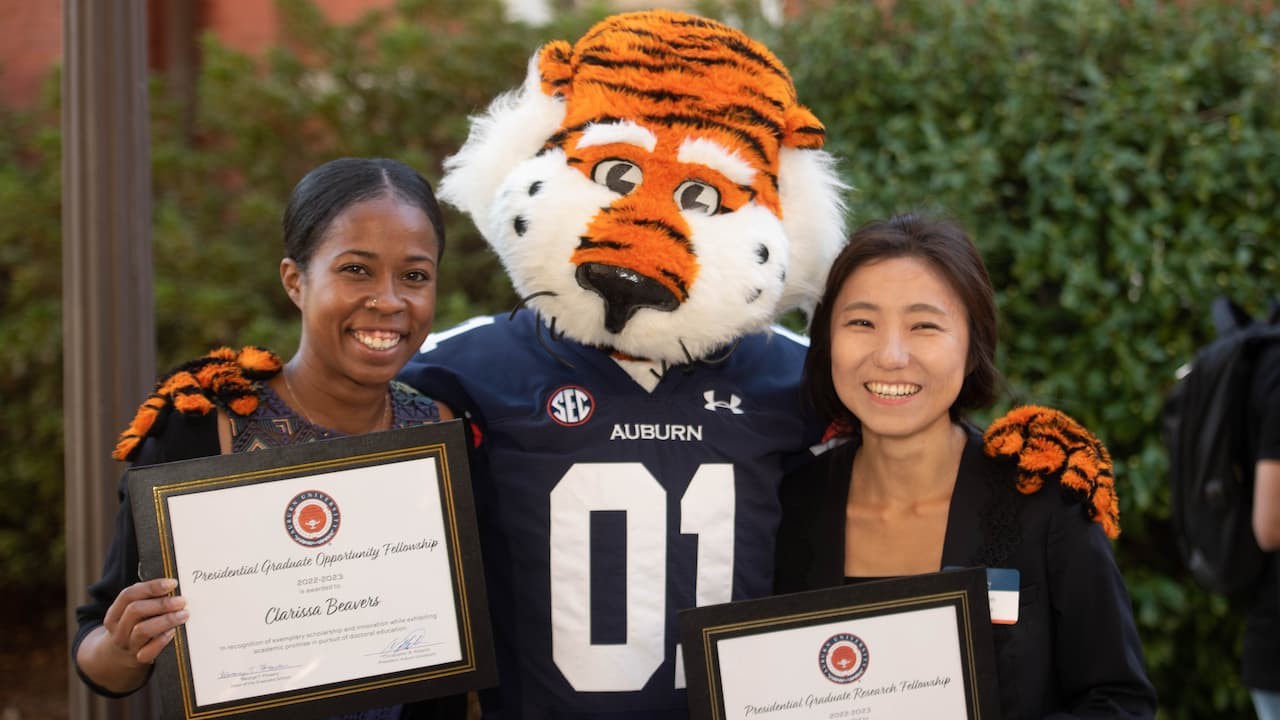 two students with Aubie holding awards
