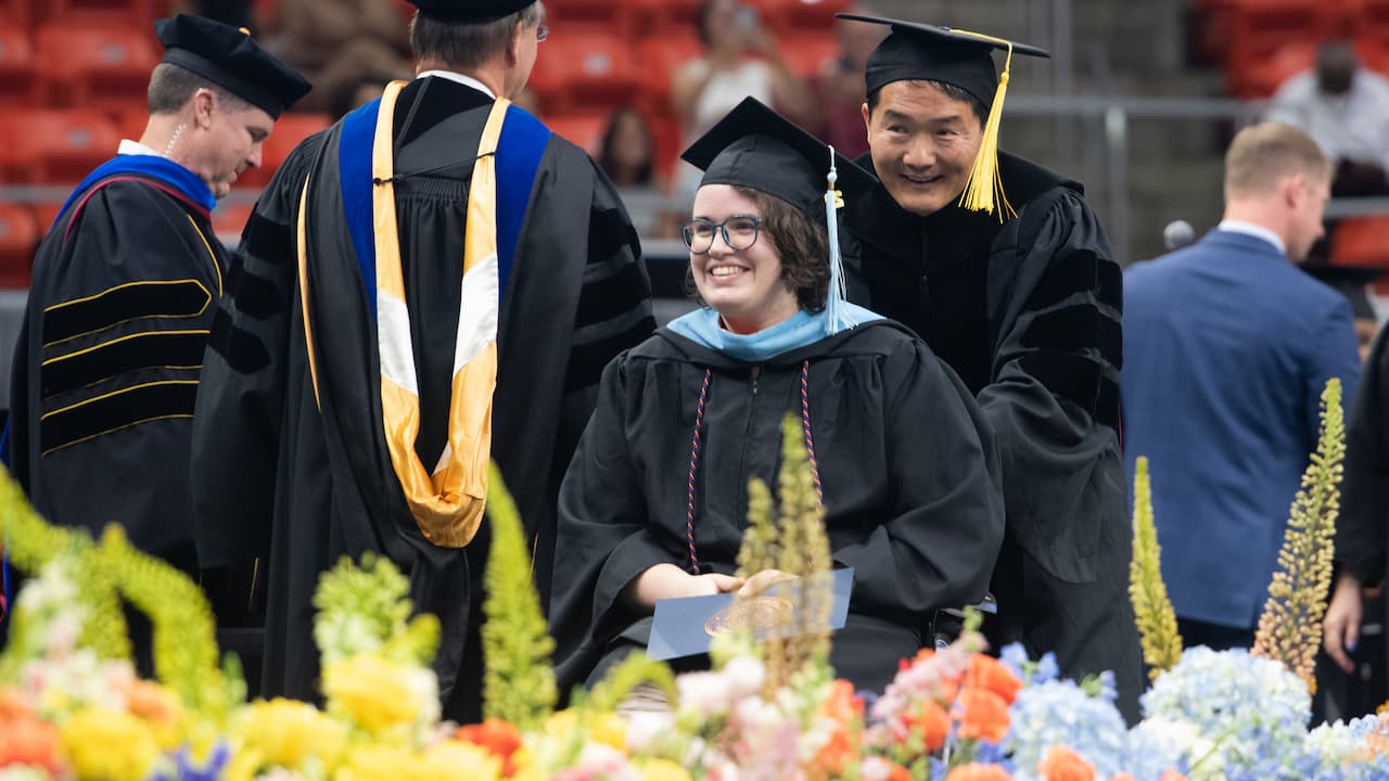 graduates in regalia walking across the stage at a commencement ceremony