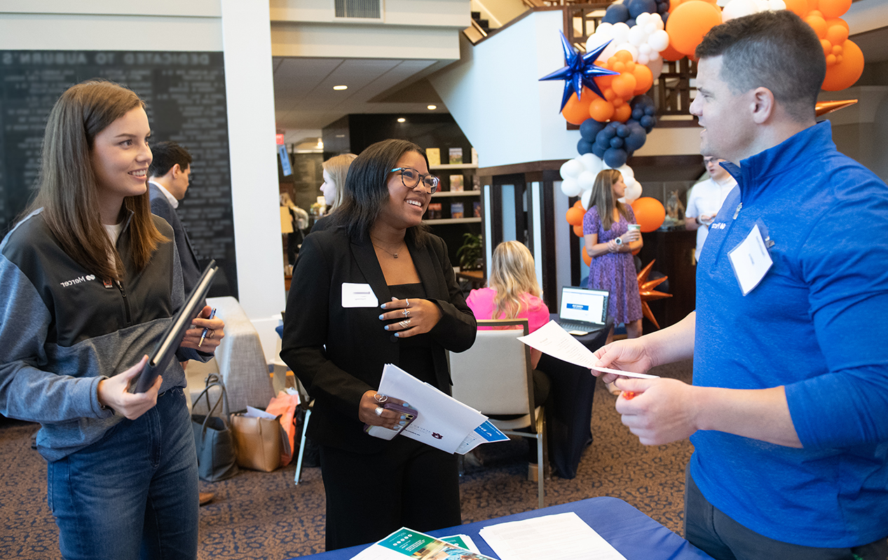 student attending a graduate recruiting fair and speaking with table representatives